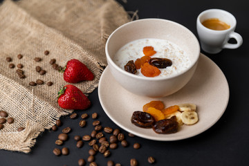 Tasty breakfast. Top view of a bowl of muesli with oats, nuts and dried fruit on black table. Slow-mo.