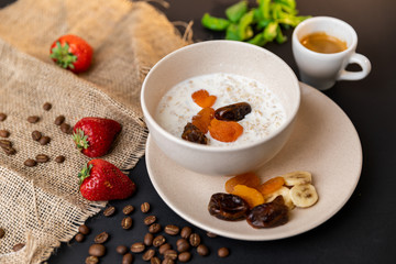 Tasty breakfast. Top view of a bowl of muesli with oats, nuts and dried fruit on black table. Slow-mo.