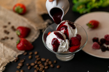 Tasty breakfast. Homemade strawberry ice cream decorated with fresh berries and mint. Black background. Slow-mo.