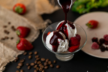 Tasty breakfast. Homemade strawberry ice cream decorated with fresh berries and mint. Black background. Slow-mo.