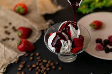 Tasty breakfast. Homemade strawberry ice cream decorated with fresh berries and mint. Black background. Slow-mo.