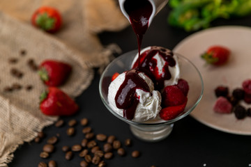 Tasty breakfast. Homemade strawberry ice cream decorated with fresh berries and mint. Black background. Slow-mo.