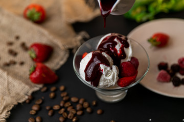 Tasty breakfast. Homemade strawberry ice cream decorated with fresh berries and mint. Black background. Slow-mo.