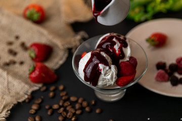 Tasty breakfast. Homemade strawberry ice cream decorated with fresh berries and mint. Black background. Slow-mo.