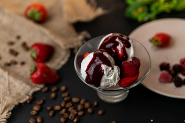 Tasty breakfast. Homemade strawberry ice cream decorated with fresh berries and mint. Black background. Slow-mo.