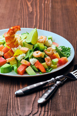 Salad with avocado, feta cheese and shrimps on old wooden table