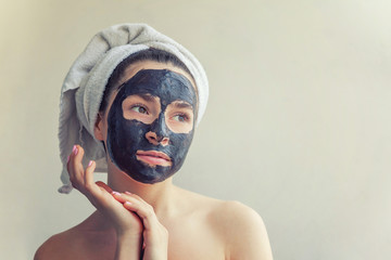 Beauty portrait of woman in towel on head applying black nourishing mask on face, white background isolated. Skincare cleansing eco organic cosmetic spa relax concept