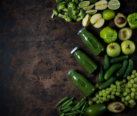 The concept of healthy organic food. Fresh green vegetables and fruit around bottles of green smoothie. Vegetable protein for vegetarianism.