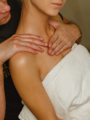 Professional male masseur doing massage for woman client at spa salon, studio. Warm romantic illumination, low key.