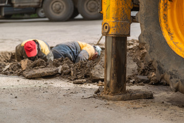 Several workers in overalls, digging a hole for troubleshooting.