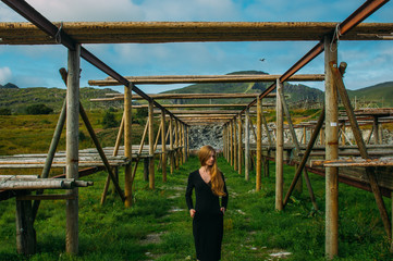 Fototapeta premium Beautiful girl in black dress posing near fish dryers