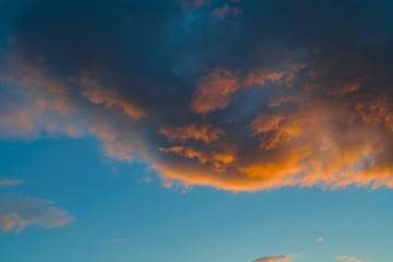 Blue sky with gold clouds - dramatic sunset, beautiful natural background. Setting sun illuminates the clouds.