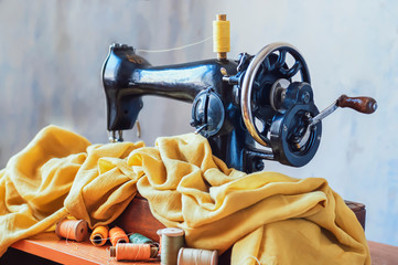 Old sewing machine, fabric and sewing thread in vintage style.