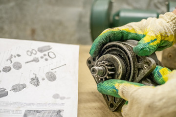 Mechanic repairing a starter on a wooden table with instructions