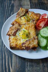 Grilled sandwich with egg, vegetables and bacon on a dark wooden background. Tasty breakfast.