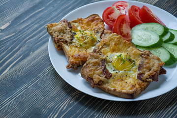 Grilled sandwich with egg, vegetables and bacon on a dark wooden background. Tasty breakfast.