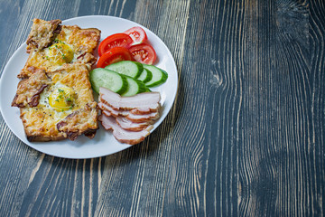 Grilled sandwich with egg, vegetables and bacon on a dark wooden background. Tasty breakfast.Place for text.