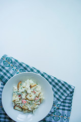 Salad with crackers, crab sticks, chicken fillet, fresh greens and hard cheese, seasoned with mayonnaise oil, served in a white plate. Salad with mayonnaise. White background. Space for text.
