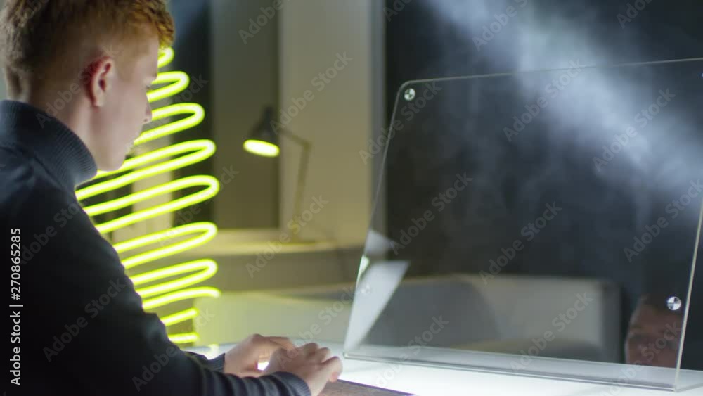 Aufkleber back view of young caucasian man sitting at glass ar screen of futuristic computer and typing on wir