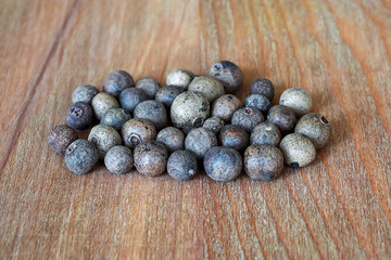 Heap of allspice berries on a brown wooden cutting board. Natural food spices and seasonings. Tasty eating.
