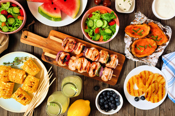 Summer picnic or BBQ food concept. Selection of fruits, salad, grilled meat and potatoes. Above...