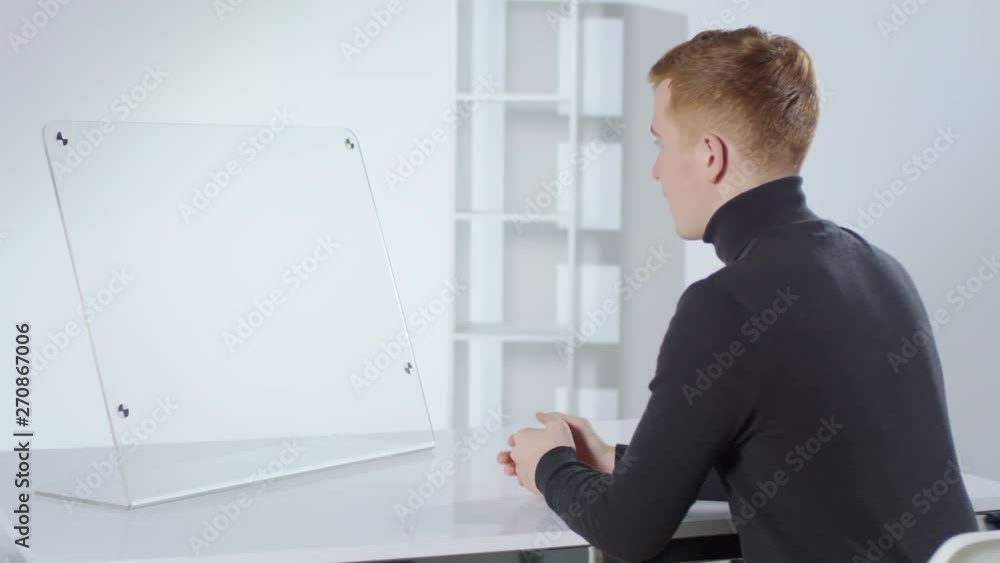 Aufkleber rare view of young caucasian man sitting at desk at invisible ar interface and having online convers