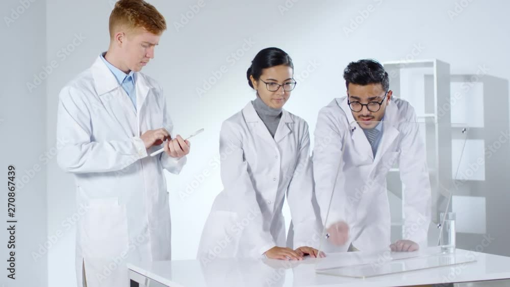 Aufkleber medium shot of three diverse doctors in lab coats standing together at hi-tech desk at glass ar disp