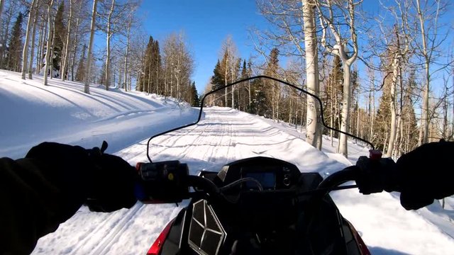 POV clip as man rides the skimobile fastly in the forest road. Camera is attached to the helmet as man drives the snowmobile in the fast manner.