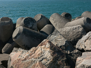 Fototapeta na wymiar Breakwater made of boulders, rocks and moulded concrete with blue ocean water in background