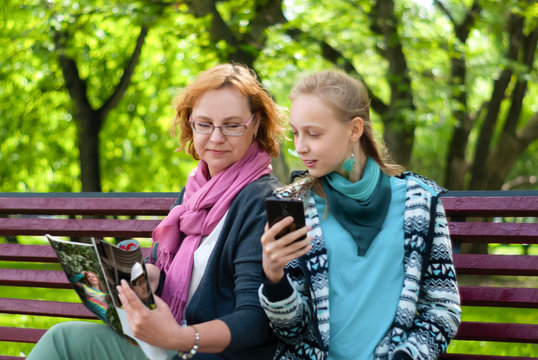 Mom And Daughter Read A Magazine In The Park