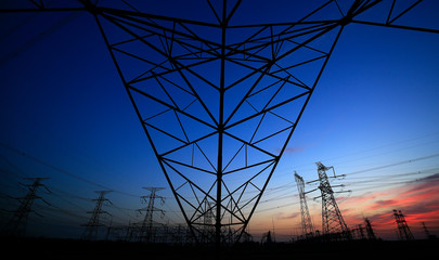 A silhouette of a high voltage tower at sunset