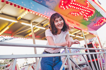 Fototapeta na wymiar Beautiful asian girl in an amusement park, smiling