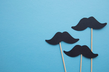 Black paper mustache on a blue background. Father's day or mens health concept