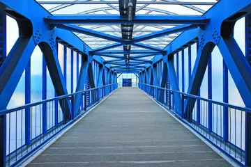 Stoff pro Meter Der Ausblick auf einen langen Korridor einer Fußgängerbrücke aus hellblauer Eisenkonstruktion © Inna
