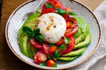 Mozzarella, tomatoes and avocado with basil and olive