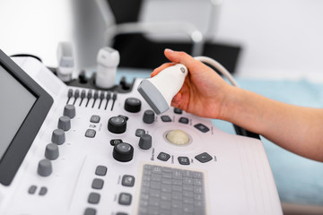 Ultrasound sensor of modern ultrasonic scanner in young woman doctor's hands preparing for a device scan. Helthcare concept