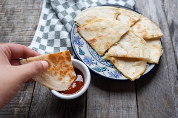 Mexican quesadillas cutted in triangle with flour tortillas and red sauce