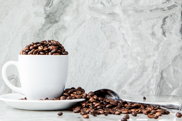 Black coffee in cup and coffee beans on marble background. Top view, space for text