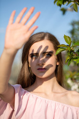 young woman covered her face from the sun with her hand outdoors.