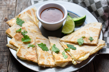 Mexican quesadillas cutted in triangle with flour tortillas and red sauce