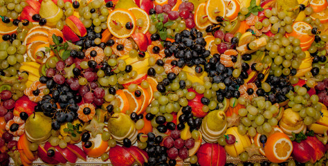 Fototapeta na wymiar Assortment of healthy raw fruits, platter background, apple, pear, grapes, orange, mandarin, top view, selective focus