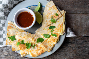 Mexican quesadillas cutted in triangle with flour tortillas and red sauce