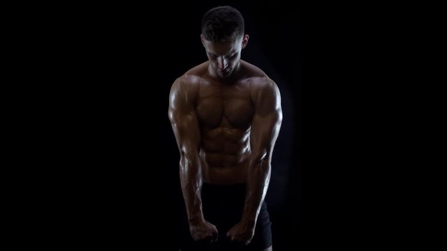 Young fit guy posing, showing muscles of upper body, slow motion