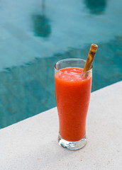 Fresh orange papaya juice in glass with bamboo tube on a  stone background near waterpool. Tropical Fruit. Top view. Free text space.