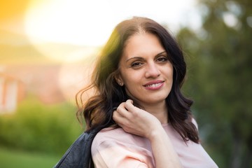 Beautiful middle-age woman in black leather jacket smiling broadly enjoying life. Springtime, outdoors;