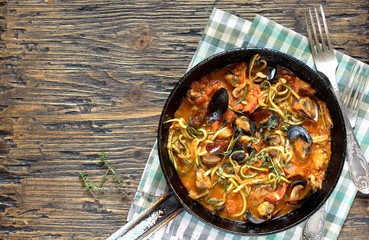Keto Pasta Zucchini (noodles) Zoodles Spaghetti With Mussels In Tomato Sauce In A Frying Pan. Low-Carb keto. Spaghetti Tarantina. top view. copy space. space for text. recipes for fatty protein foods 