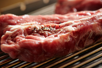 Fresh raw meat with seasoning on grill
