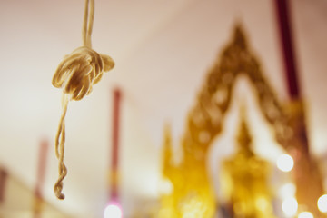 Closeup holy thread With blurred Buddha in the temple, Concept prayer service at a temple on New Year For prosperity.