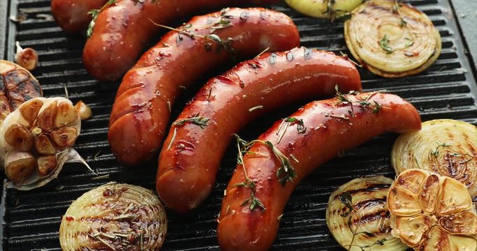 Grilled sausage with the addition of herbs and vegetables on the grill plate, outdoors. Grilling food, bbq, barbecue, 4k