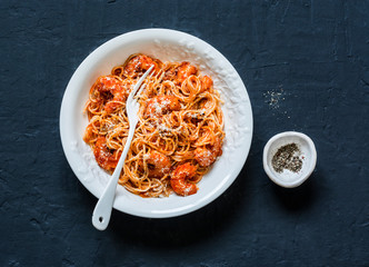 Shrimp tomato sauce spaghetti on a dark background, top view